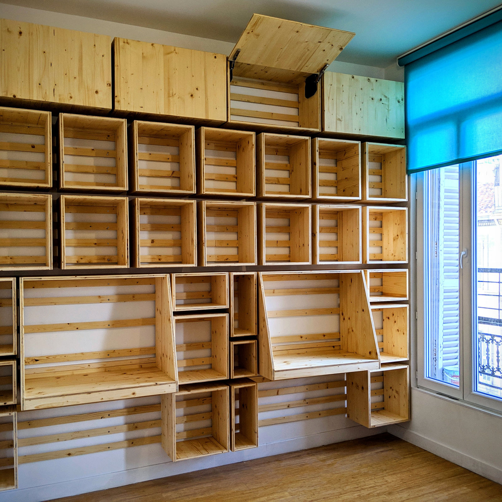 Ensemble de rangements muraux en bois, avec niches et caissons ouverts.